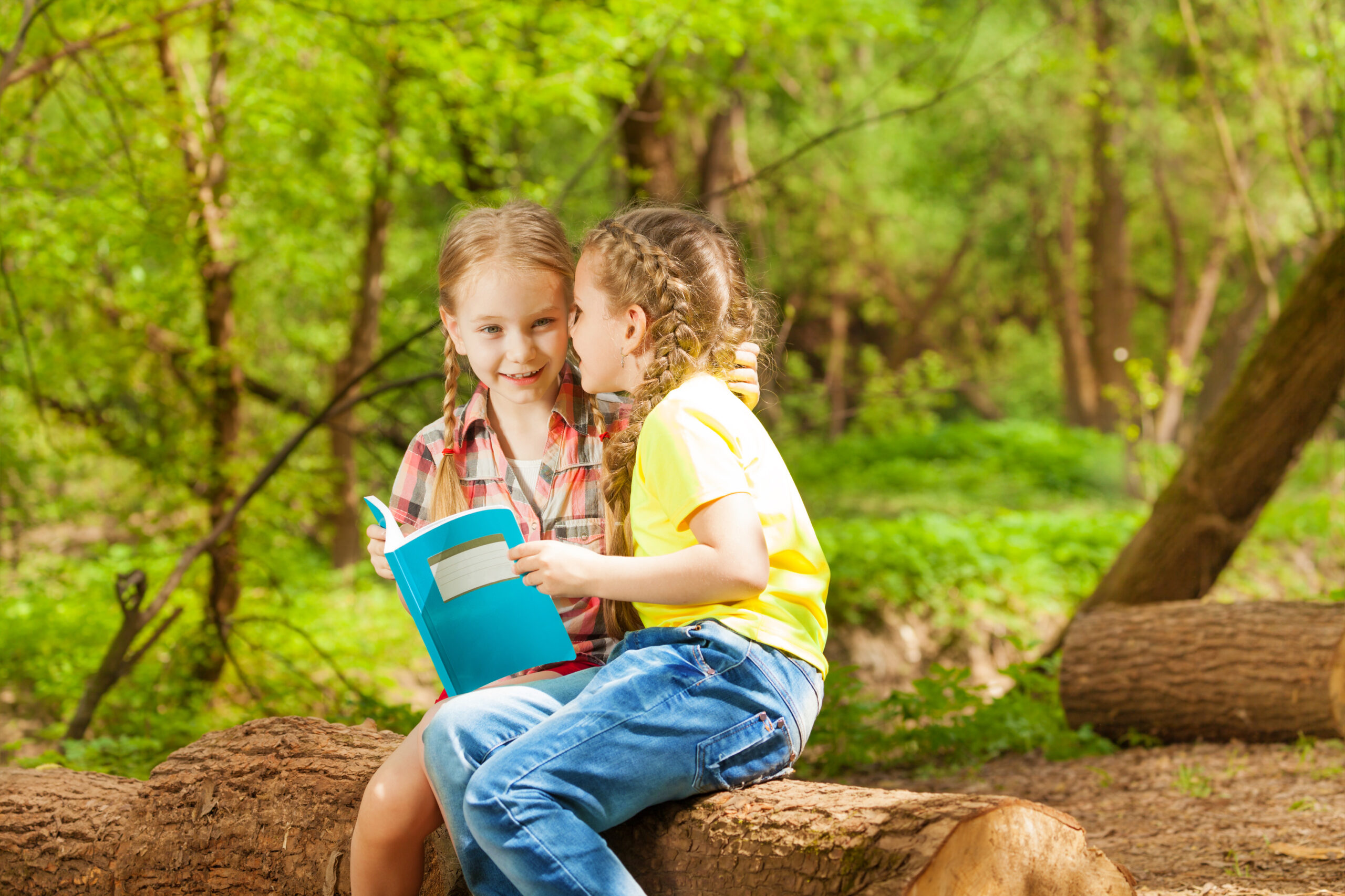 two friends whispering secrets sitting at park