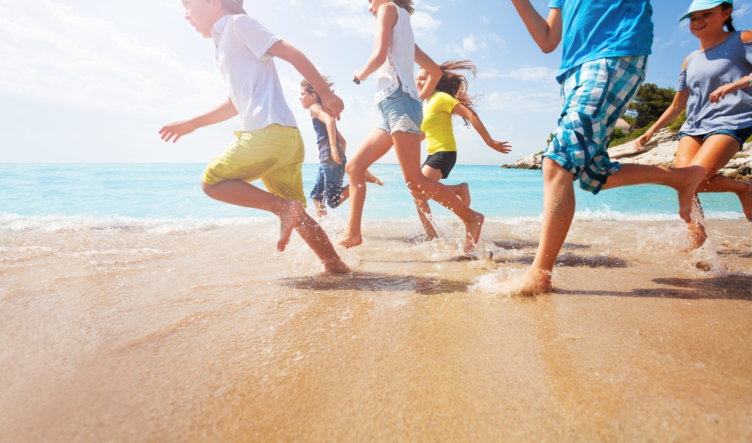 close up of running kids legs in shallow sea water