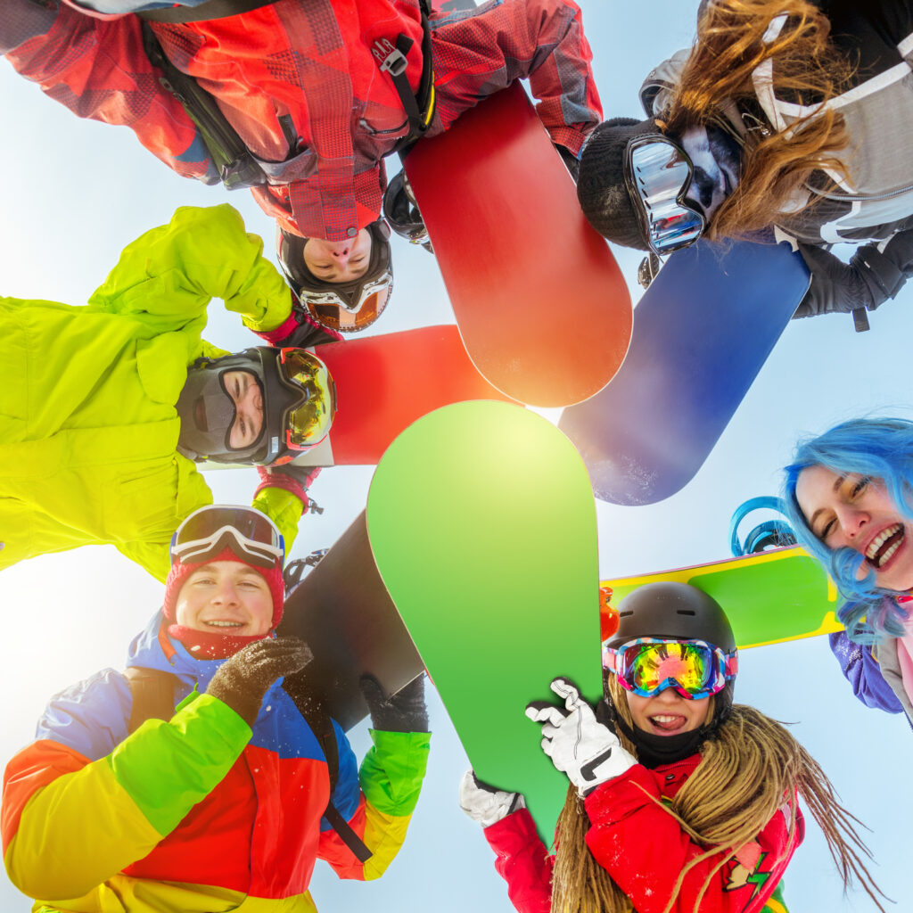 group of happy friends stands in circle with snowboards