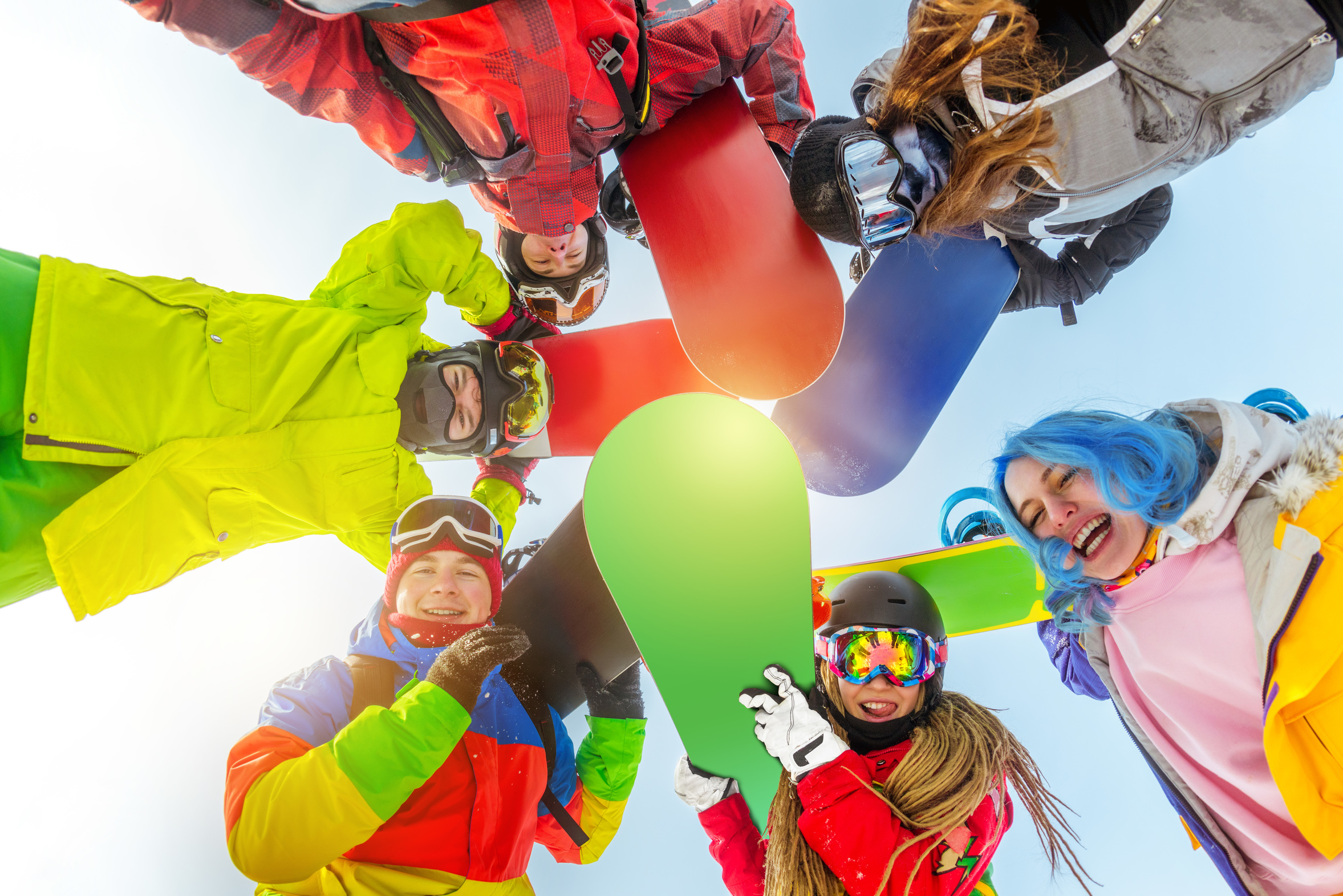 group of happy friends stands in circle with snowboards