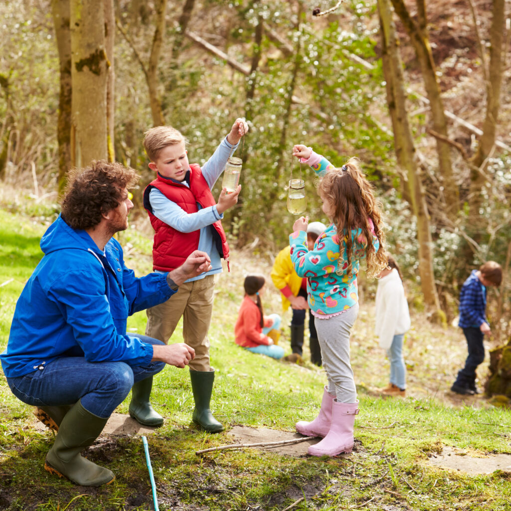 adults and children exploring pond at activity centre