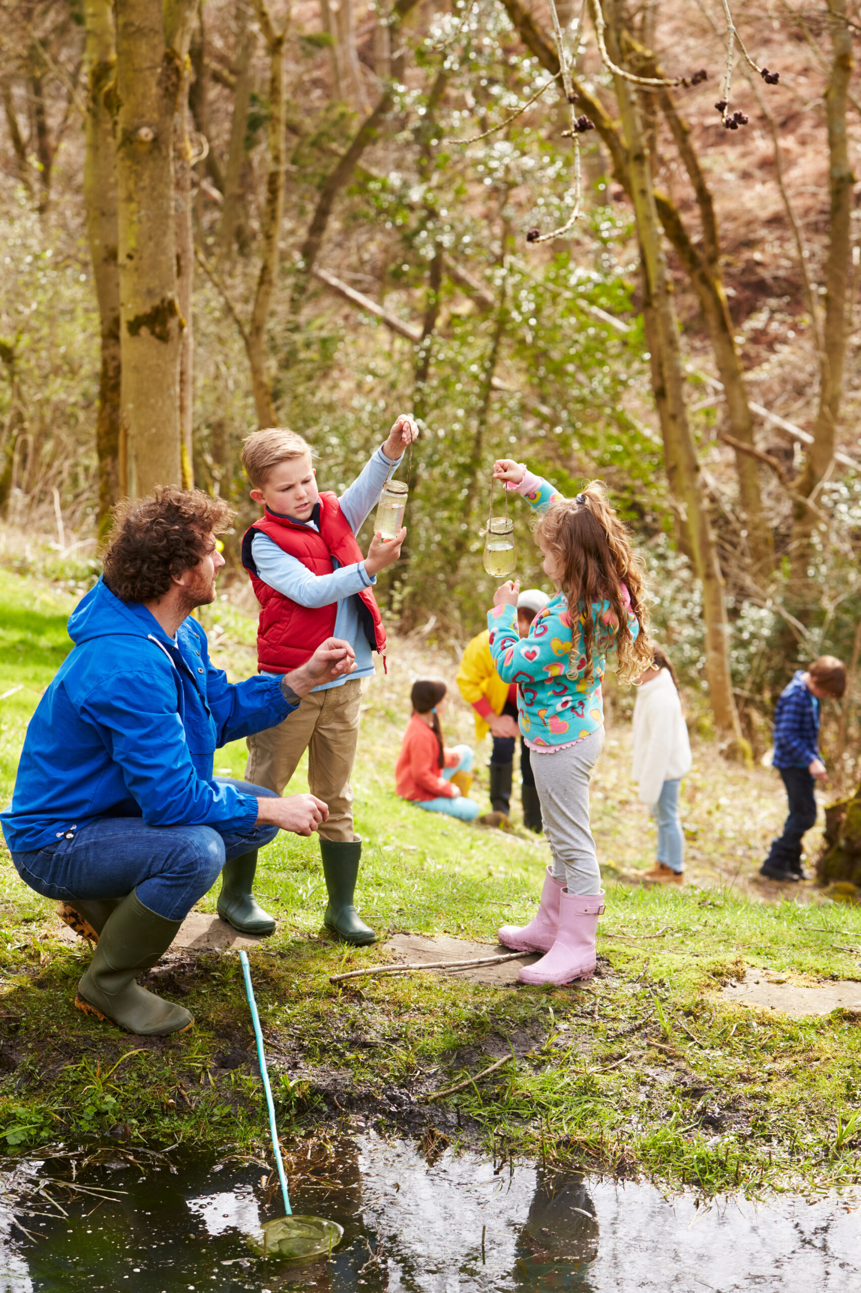 adults and children exploring pond at activity centre